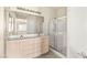 Well lit bathroom with dual sinks, white cabinets, and glass enclosed shower at 199 Bailey Island Dr, Henderson, NV 89074