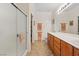 Bright, spacious bathroom featuring a shower, dual sinks with wooden cabinets, and tile flooring at 2108 Willow Wren Dr, North Las Vegas, NV 89084