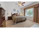 Comfortable carpeted bedroom with a ceiling fan, a large window, and traditional-style wooden furniture at 2108 Willow Wren Dr, North Las Vegas, NV 89084