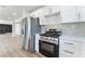 Modern kitchen with stainless steel fridge and range, white cabinets, and stone backsplash at 2180 Palora Ave, Las Vegas, NV 89169