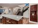 Kitchen island with granite countertop and stainless steel microwave next to a dark wood staircase at 2435 Granada Bluff Ct, Las Vegas, NV 89135