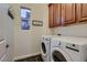 Bright laundry room featuring a modern washer and dryer, dark floors, cabinets, and wall-mounted coat rack at 2435 Granada Bluff Ct, Las Vegas, NV 89135