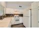 Bright kitchen features white cabinets, stainless steel sink, modern laminate floor, and mosaic backsplash at 318 Heather Dr, Henderson, NV 89002