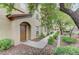 Inviting entrance with an arched doorway, brown door, and manicured shrubs along a walkway at 3930 Legend Hills St # 102, Las Vegas, NV 89129