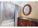 Elegant bathroom with a stylish vanity, round mirror, decorative wood-carved cabinet and shower with stone-look tiling at 4323 E Twain Ave, Las Vegas, NV 89121