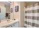 Bright bathroom features a single vanity, an extra wide mirror and a shower-tub combo with a striped curtain at 4521 Bell Cord Ave # 103, North Las Vegas, NV 89031