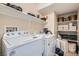 Bright laundry room with white washer and dryer, shelves, and neutral color scheme at 4521 Bell Cord Ave # 103, North Las Vegas, NV 89031