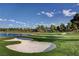 Scenic golf course view featuring a sand trap, lush green, blue lake, and luxurious homes in the background at 5112 Onion Creek Ln, Las Vegas, NV 89113