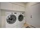 Functional laundry room featuring white front-load washer and dryer with built-in storage cabinets at 5112 Onion Creek Ln, Las Vegas, NV 89113