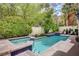 Backyard oasis featuring swimming pool and spa with blue tiled accents, surrounded by lush greenery at 5112 Onion Creek Ln, Las Vegas, NV 89113