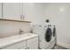 Well-equipped laundry room boasts a modern washer and dryer set, complemented by a practical sink and storage cabinets at 5321 Brayden Ct, Las Vegas, NV 89131