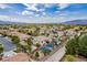 Aerial view showing a lush community, pool, tennis court, landscaping, and surrounding desert at 6214 Ebony Legends Ave, Las Vegas, NV 89131