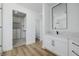 Bathroom with white vanity, large mirror, and walk-in closet with built-in shelving at 6214 Ebony Legends Ave, Las Vegas, NV 89131