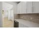 Close-up of butler's pantry featuring sleek countertops, tiled backsplash, and convenient wine refrigerator at 6214 Ebony Legends Ave, Las Vegas, NV 89131
