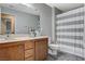 Bathroom with neutral paint, wooden cabinets, light countertops, and grey striped shower curtain at 7042 Grand Junction Ave, Las Vegas, NV 89179
