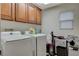 Well-lit laundry room featuring a washer, dryer, and overhead cabinets for storage at 7042 Grand Junction Ave, Las Vegas, NV 89179