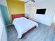 This bedroom has a bed with a red frame, light gray wood-look floors, and a television mounted on the wall at 7319 Burnt Umber St, Las Vegas, NV 89139