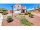 Two-story home with a two-car garage, red rock landscaping, and blooming bushes on a sunny day at 7892 Villa Salsa Ave, Las Vegas, NV 89131