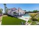 This backyard features artificial turf, a swimming pool, and mature landscaping at 100 Huntly Rd, Las Vegas, NV 89145