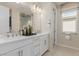 En Suite bathroom with dual sinks, white cabinets and a large mirror at 10316 Apefly St, Las Vegas, NV 89141
