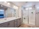 Bright bathroom features double sinks, gray cabinets, large mirror, and glass shower with tile surround at 10590 Dryades Ave, Las Vegas, NV 89166
