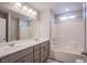 Bright bathroom boasts dual sinks, large mirror, gray vanity and a tub/shower combo with tiled surround at 10590 Dryades Ave, Las Vegas, NV 89166