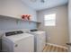 Well-lit laundry room features wood-look flooring, new washer and dryer, and shelving at 10590 Dryades Ave, Las Vegas, NV 89166