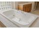 Close-up of a large soaking tub with jets and a tile surround in bathroom at 10761 Capesthorne Way, Las Vegas, NV 89135