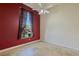 Bedroom features red accent wall, travertine flooring, ceiling fan, and window at 10761 Capesthorne Way, Las Vegas, NV 89135