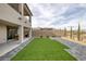 A large, landscaped backyard featuring a synthetic lawn, paved patio, and a block fence for privacy at 180 Native Stone St, Las Vegas, NV 89138