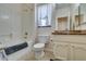 Bright bathroom with a shower over bath, toilet, and vanity with light-colored cabinets at 2114 High Mesa Dr, Henderson, NV 89012