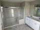 Bright bathroom featuring a glass-enclosed shower and double vanity with white cabinets at 2456 Bagnara Pl, Henderson, NV 89044