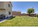 A broad view of a green backyard, featuring well-kept grass and a stainless steel grill near the home at 4050 Midnight Crest Ave, North Las Vegas, NV 89031