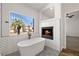 Bright bathroom featuring a modern tub with a fireplace and a large window at 4607 El Camino Cabos Dr, Las Vegas, NV 89147