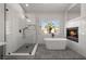 Luxurious bathroom featuring a freestanding tub, fireplace, and herringbone-tiled shower at 4607 El Camino Cabos Dr, Las Vegas, NV 89147