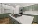 Modern kitchen featuring green cabinets, a center island with cooktop, and white countertops at 4607 El Camino Cabos Dr, Las Vegas, NV 89147