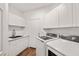 Well-lit laundry room with white cabinets, sink, and modern washer and dryer units at 4607 El Camino Cabos Dr, Las Vegas, NV 89147