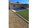 Spacious backyard with artificial grass, concrete patio, stone landscaping, and partial house view at 4690 E California Ave, Las Vegas, NV 89104