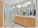 Bathroom featuring a double sink vanity with natural wood finish, large mirrors, and a glass enclosed shower at 5068 Rivedro St, Las Vegas, NV 89135