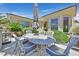 Outdoor patio space with ornate white metal table, chairs and umbrella, surrounded by desert landscaping at 5068 Rivedro St, Las Vegas, NV 89135