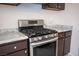 Close up of the stainless steel stove in kitchen with dark brown cabinets and white countertops at 5241 Janfred Ct # 18, Las Vegas, NV 89103