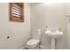 Cozy powder room featuring a pedestal sink, toilet, and shuttered window at 5380 Flowing Spring St, Las Vegas, NV 89122