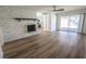 Bright living room features a white brick fireplace, light wood flooring, and access to kitchen and backyard at 6842 Greengrove Dr, Las Vegas, NV 89103