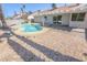 Backyard with a pristine pool, complemented by a covered patio and desert landscaping at 6842 Greengrove Dr, Las Vegas, NV 89103