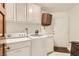 Clean laundry room with white cabinets, washer, dryer, and a door to another area at 7296 Mission Hills Dr, Las Vegas, NV 89113