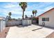 View of the backyard with a concrete patio, storage sheds, block wall, and mature palm trees at 1158 E Hacienda Ave, Las Vegas, NV 89119