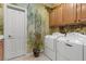 Bright laundry room features a side-by-side washer and dryer, artistic accent wall, and ample storage cabinets at 2151 Bannerwood St, Henderson, NV 89044