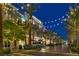 Evening view of a community retail street featuring lights, storefronts, and palm trees at 2185 High Mesa Dr, Henderson, NV 89012