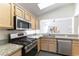 Well-equipped kitchen featuring stainless steel appliances, granite countertops, light wood cabinetry, and pass through window at 2185 High Mesa Dr, Henderson, NV 89012