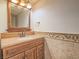 Bathroom featuring a single vanity with a neutral stone countertop, wood cabinets, and framed mirror at 2462 Pickwick Dr, Henderson, NV 89014